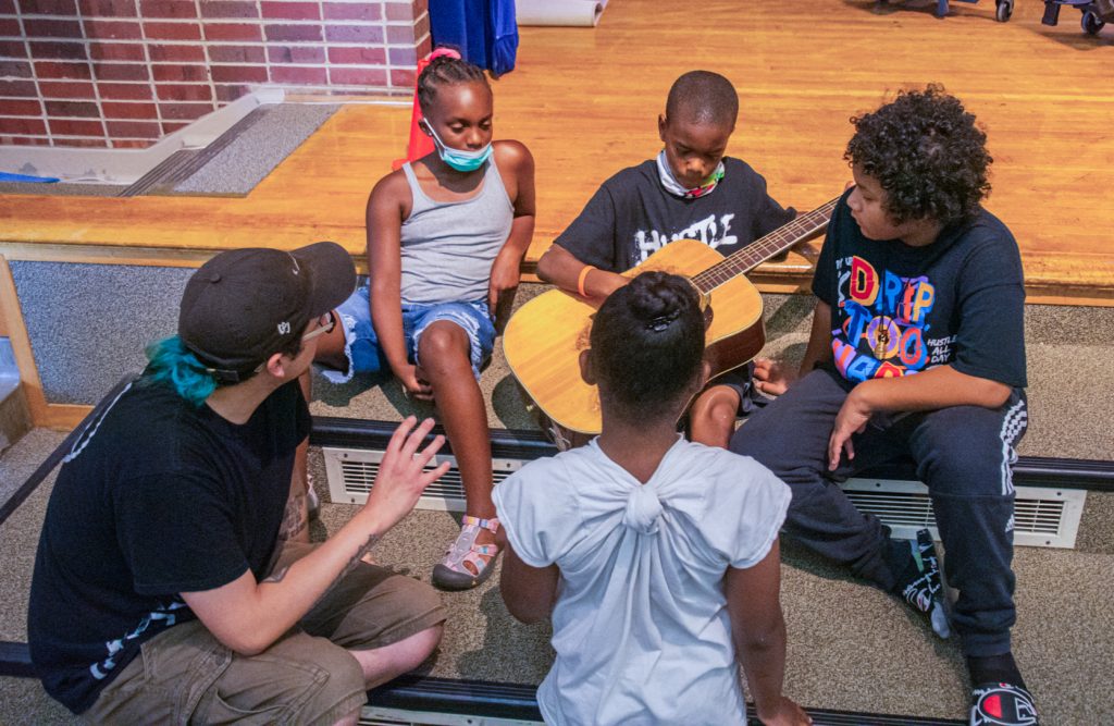 A mentor guiding a young person in the recording studio